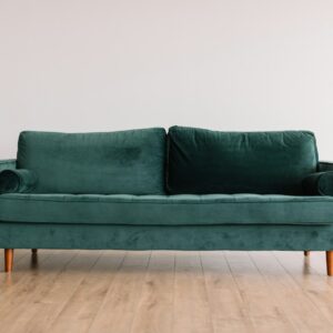 Forest green velvet three-seat sofa on a light wood floor
