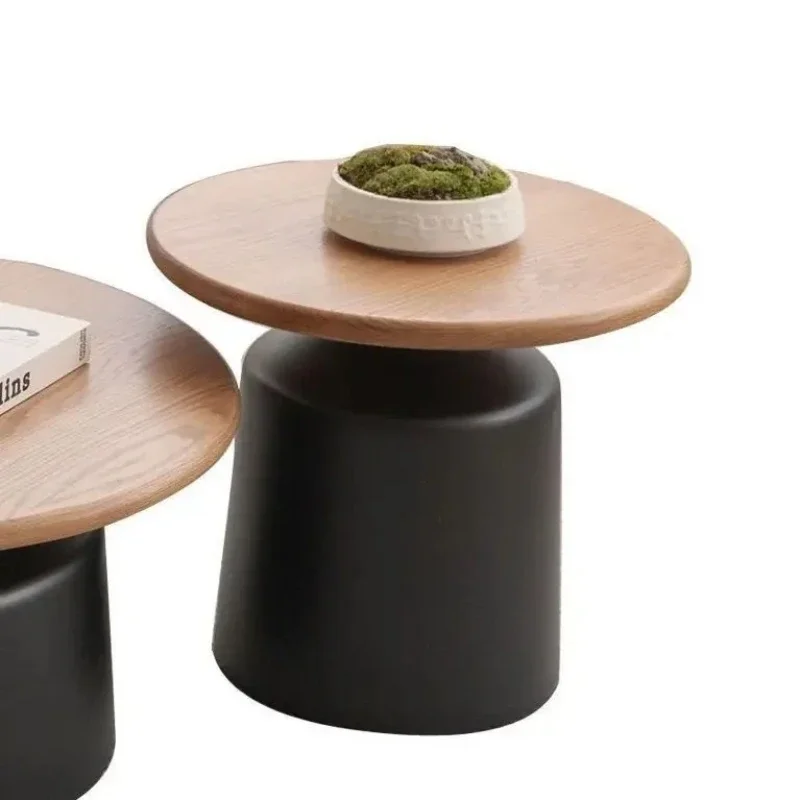 Round coffee table with a black pedestal base beside the wood-top version