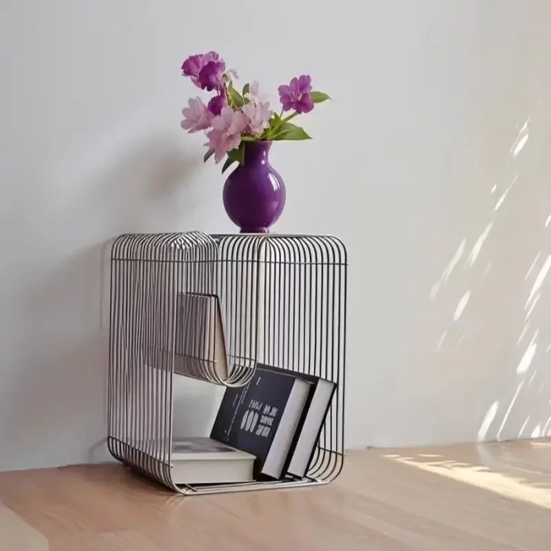 Brushed silver curved wire side table holding a small vase of flowers