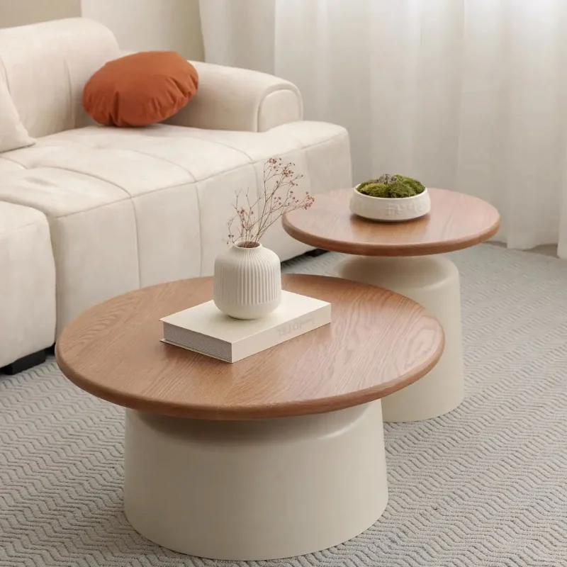 Round wood-top coffee tables with white pedestal bases arranged in front of a cream sofa
