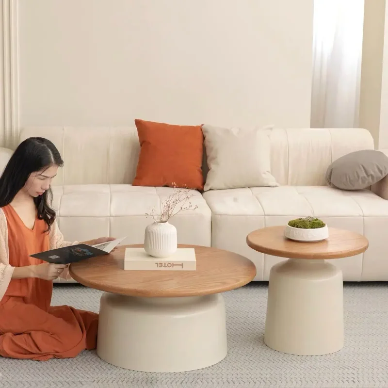 Round pedestal coffee table in a living room, a person reading on the floor beside it