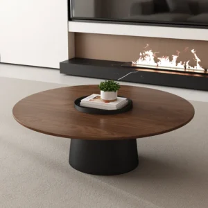 Round walnut-tone coffee table on a matte black pedestal in a living room with a fireplace