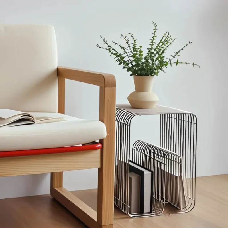 Brushed silver curved wire side table next to a cream armchair, a potted plant on the top